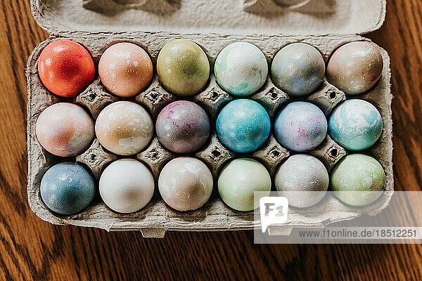 Overhead shot of dyed Easter eggs in carton sitting on kitchen table