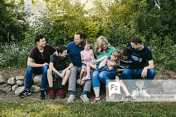 Family group laughs together in green forest with many kids