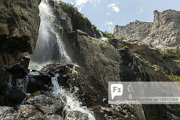 Male hiker poses below waterfall in Rocky Mountain National Park