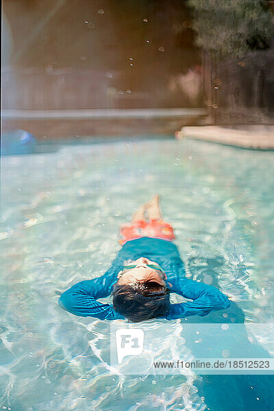 Boy relaxing on his back in a pool