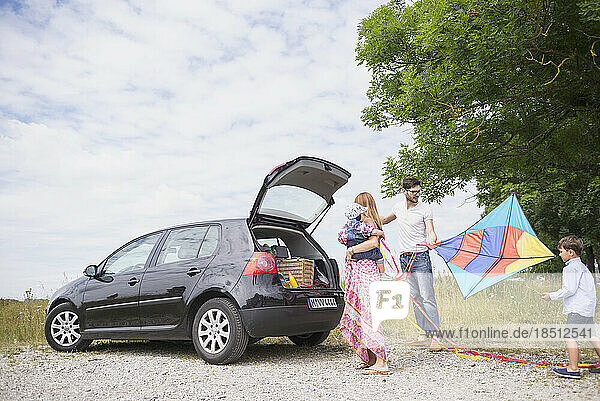 Family with kite unloading the car on meadow in the countryside  Bavaria  Germany