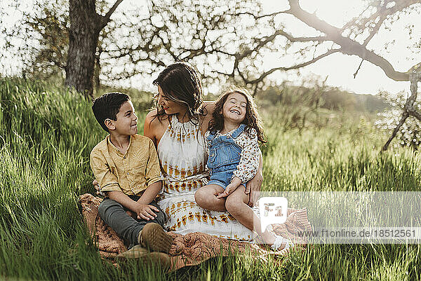 Mother  son  and daughter in backlit field smiling at each other