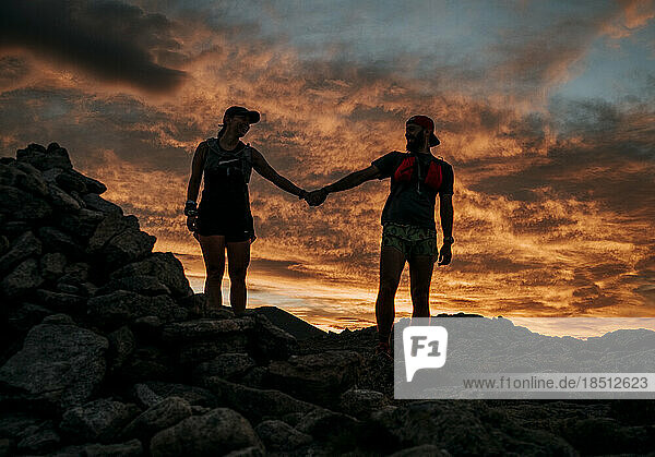 couple holds hands in front of colorful sunrise  Katahdin  Maine