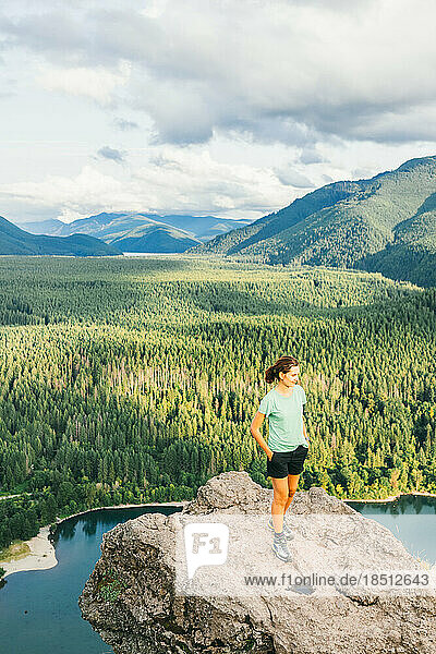 Hiker girl looking at green hills and lake from the edge in Washington