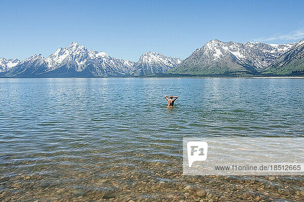Man standing in deep water in alpine lake