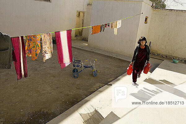 Girl carries water from neighbor's tap in Kabul.