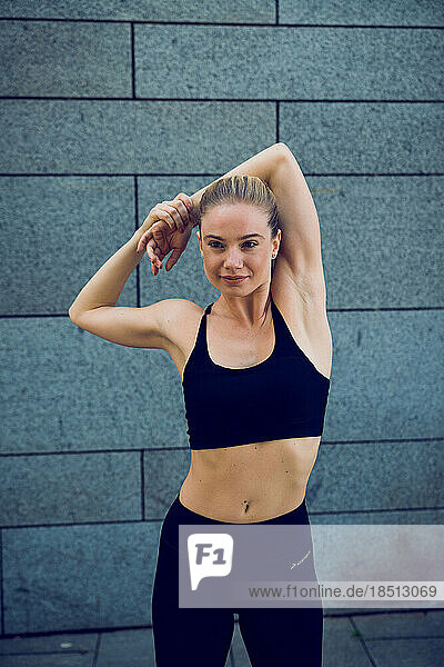 Young and beautiful woman in black sportswear stretching