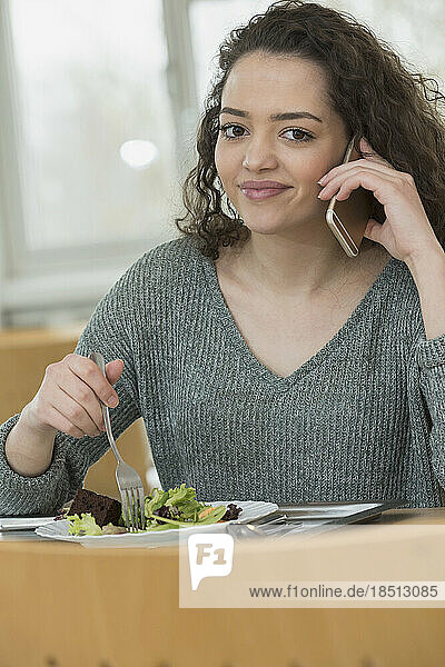 University student eating salad in canteen and talking on mobile phone School  Bavaria  Germany