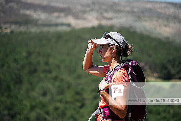 Female hiker putting on her cap on a sunny day.