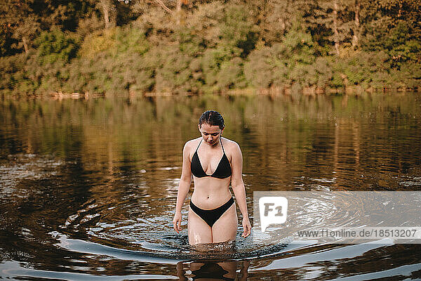 Young woman in a bikini walking in river