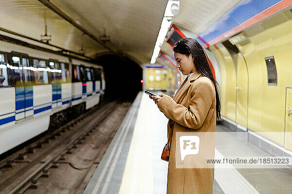 asian girl using the phone looking at the map inside the subway
