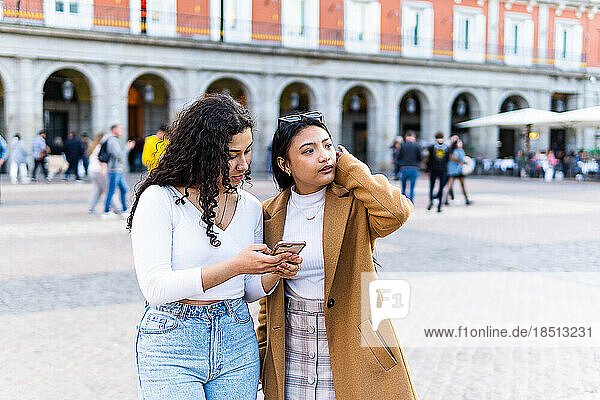 Stock photo of a two friends looking at there phone chatting.