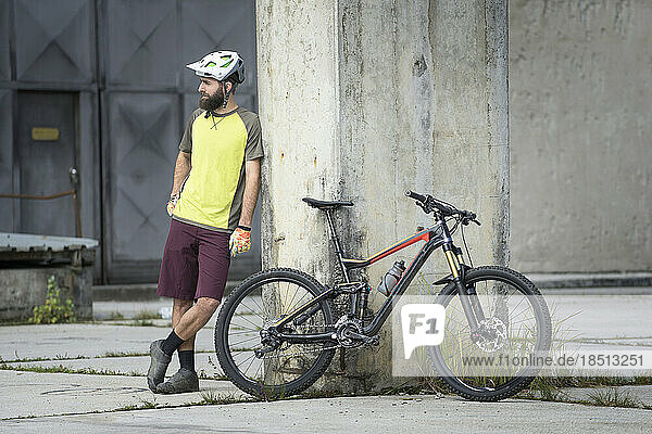 Mountain biker stands close to his bike in city