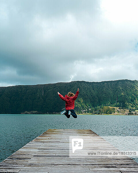 Young woman jumping on the jetty of a lake in Azores