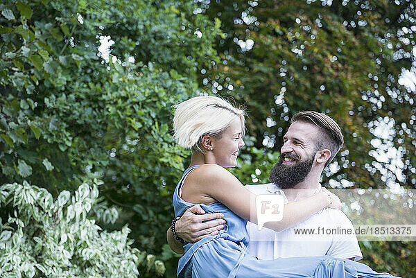 Happy young man carrying woman in garden  Bavaria  Germany