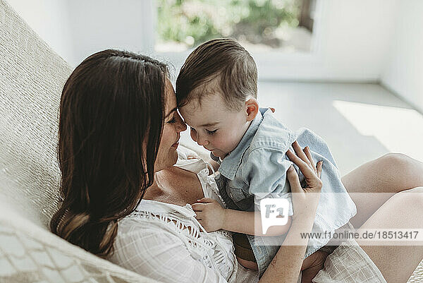 Mother and young son cuddling in hammock in natural light studio