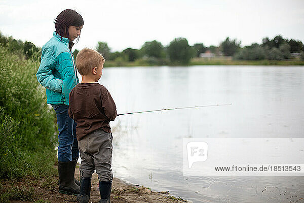 Big sister helping little brother fishing