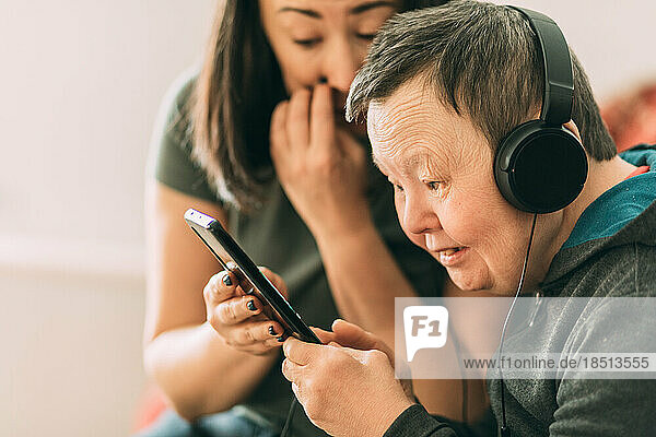 elderly woman with Down syndrome  assistant help her to use phone