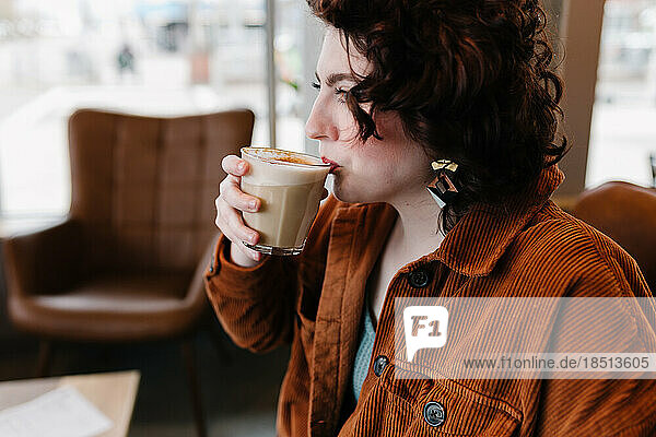Profile view of beautiful woman taking sip of latte