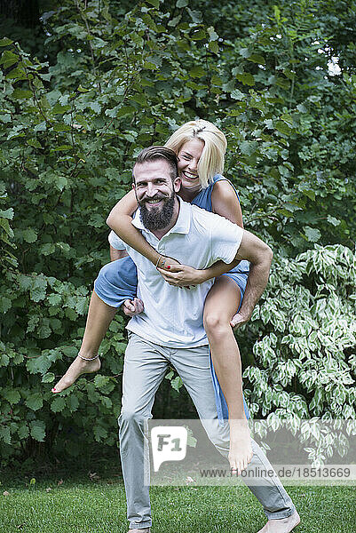 Happy woman enjoying piggyback ride on her boyfriend in garden  Bavaria  Germany