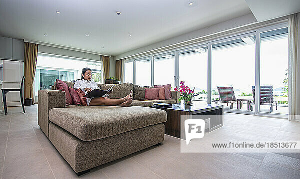 Woman relaxing on sofa at holiday flat in Phuket