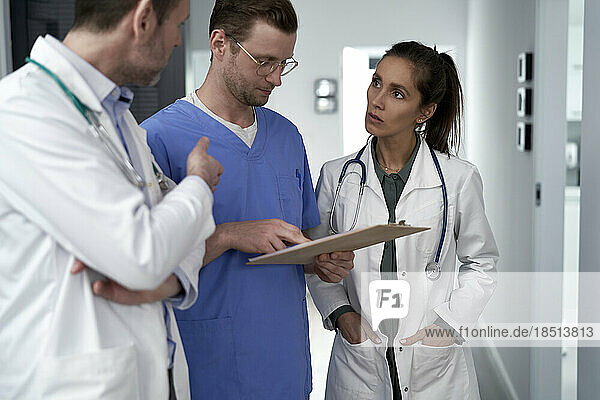 Doctor discussing with colleagues over medical record in clinic