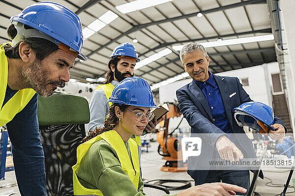 Businessman gesturing and discussing with colleagues over laptop in industry