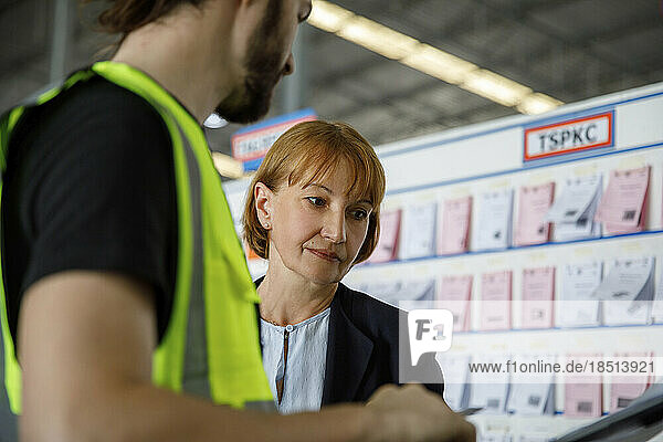 Manger examining checklist by colleague in warehouse