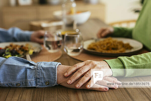 Ältere Frau stapelt Hand auf Mann am Esstisch
