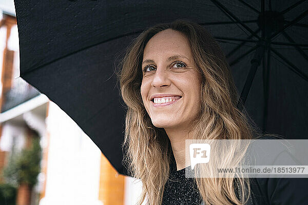 Happy woman with blond hair holding umbrella
