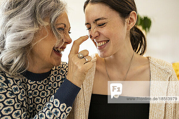 Happy mature woman applying chocolate on daughter's nose