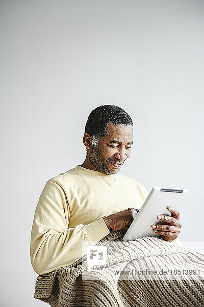Smiling mature man using tablet PC at home