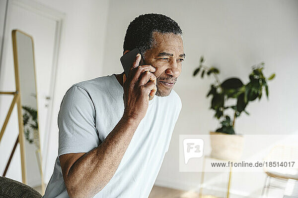 Mature man talking on smart phone at home