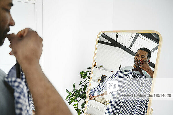 Mature man with checked shirt standing in front of mirror