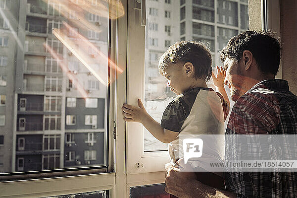 Vater und Sohn schauen zu Hause aus dem Fenster