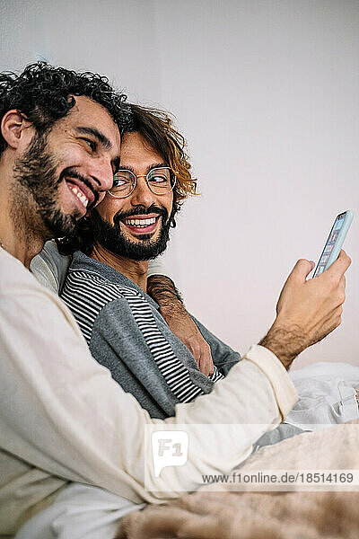 Happy gay couple with mobile phone at home