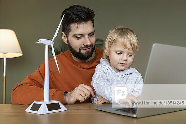 Father with son studying on laptop at home