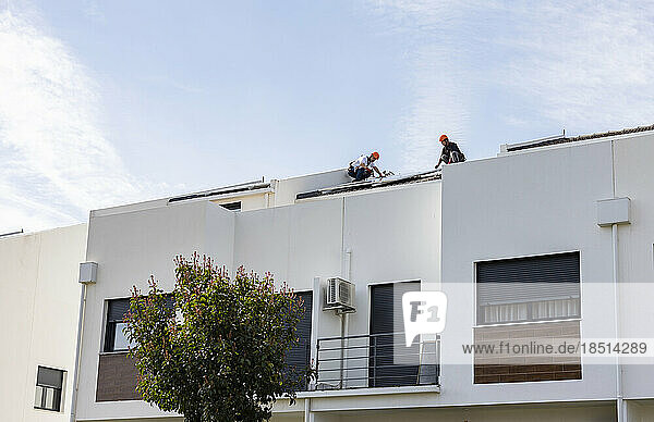 Technicians installing solar panels on roof