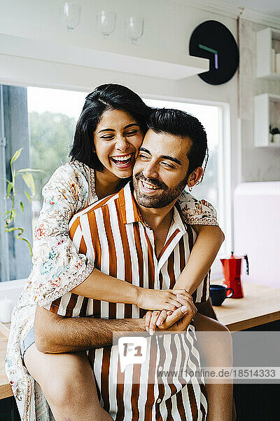 Happy woman embracing boyfriend in kitchen at home