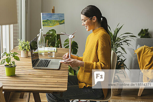 Smiling freelancer with wind turbine model talking on video call