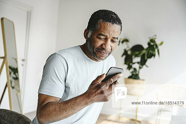 Mature man using mobile phone at home