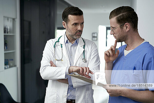 Doctors discussing over document in clinic