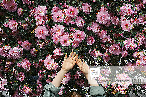Frau mit erhobenen Armen vor Blumen