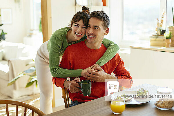 Happy woman with arm around man at home