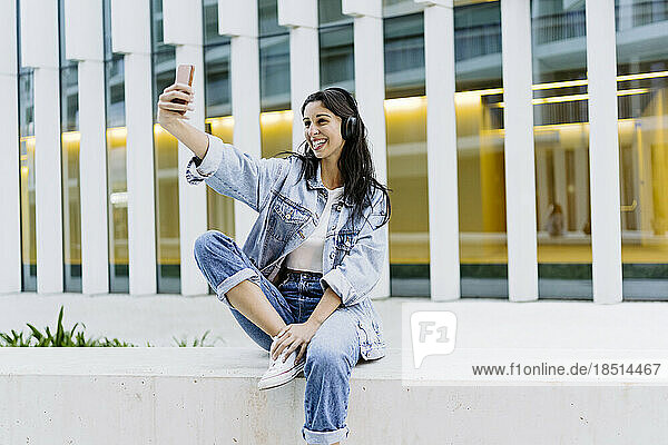 Happy young woman taking selfie through smart phone