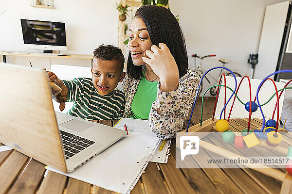 Happy mother sharing laptop with son at home
