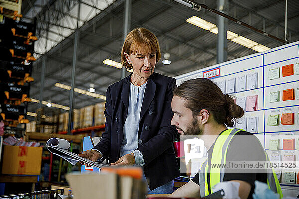 Mature manager explaining colleague over clipboard at warehouse