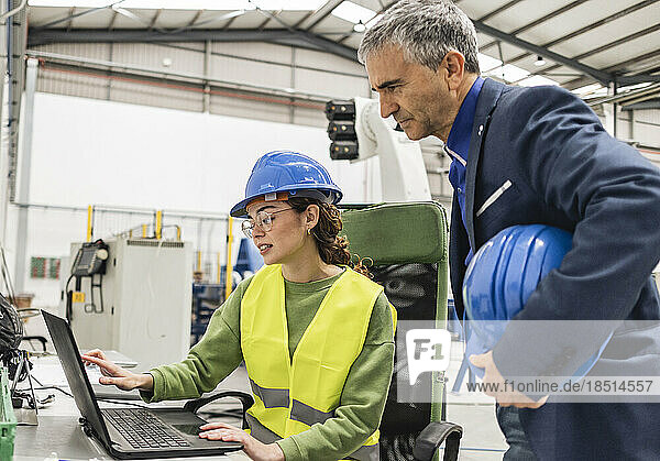 Engineers discussing over laptop in industry