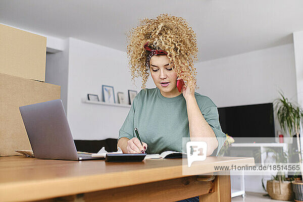Businesswoman talking on smart phone at desk