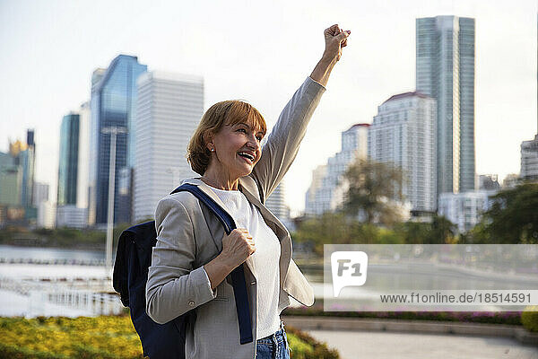 Cheerful businesswoman with clenched fist raising hand